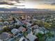 Sunset aerial view of a Nevada neighborhood highlighting mountain views, and vibrant city lights in the distance at 1501 Via Salaria Ct, Henderson, NV 89052