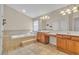 Bathroom featuring a soaking tub, dual sinks, and wood cabinets at 1501 Via Salaria Ct, Henderson, NV 89052