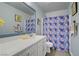 Bathroom vanity with a blue framed mirror and a colorful patterned shower curtain at 320 Point Loma Ave, North Las Vegas, NV 89031