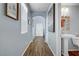 Hallway featuring wood-look tile flooring, arched doorways, light blue walls, and a powder room with a pedestal sink at 320 Point Loma Ave, North Las Vegas, NV 89031