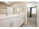 Bright bathroom with dual sinks, white cabinetry and a view into the primary bedroom at 11236 Rainbow Peak Ave # 210, Las Vegas, NV 89135
