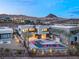 Modern home with a beautiful backyard pool and desert mountain views at twilight in a gated community at 12 Falling Canyon Ct, Henderson, NV 89011