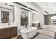 Bright bathroom showcasing a soaking tub with rock decor, modern cabinetry, and large windows at 12 Falling Canyon Ct, Henderson, NV 89011