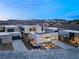 Modern home featuring desert landscaping, a three car garage, and stylish exterior lighting at twilight at 12 Falling Canyon Ct, Henderson, NV 89011