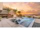 Luxurious outdoor pool area with palm trees, a built-in fire pit, and a beautiful sunset view at 12 Falling Canyon Ct, Henderson, NV 89011