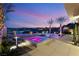 Captivating pool and spa area with ambient lighting, complemented by palm trees and distant mountain views at 12 Falling Canyon Ct, Henderson, NV 89011