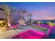Beautiful backyard featuring a modern pool with colorful lighting, accompanied by palm trees and a cozy fire pit at 12 Falling Canyon Ct, Henderson, NV 89011