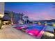 Spectacular pool area with vibrant lighting, accentuated by palm trees and elegant water features against the sunset at 12 Falling Canyon Ct, Henderson, NV 89011