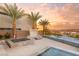 Backyard pool area with palm trees, a spa, a fire pit, and views of the mountains and sunset at 12 Falling Canyon Ct, Henderson, NV 89011