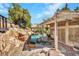 Backyard pool area features a custom rock waterfall, spa, and covered patio with flagstone at 125 Firecreek Cir, Las Vegas, NV 89107