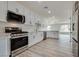 Open concept kitchen with stainless steel appliances, sleek white cabinets, and hardwood floors at 1400 Cottonwood Pl, Las Vegas, NV 89104
