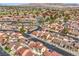 An aerial view of a neighborhood with red-tiled roofs, palm trees, and a golf course, nestled against a mountain backdrop at 2727 Scotch Heather St, Las Vegas, NV 89142