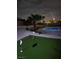 Backyard with putting green, palm trees, rock features, and a lit pool at 2749 Horseshoe Dr, Las Vegas, NV 89120