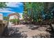 Spacious backyard features a gravel area, brick patio, mature trees, and a wooden deck with tiered seating at 2819 Prickley Pear Dr, Henderson, NV 89074