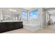 Bright primary bath featuring a soaking tub, dual vanity with dark cabinets, and large windows at 3062 Echoed Rondel Ln, Henderson, NV 89044