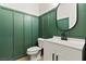 Stylish powder room featuring striking green paneled walls, a modern vanity, and a round mirror at 3062 Echoed Rondel Ln, Henderson, NV 89044