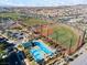 Aerial view of a neighborhood pool, baseball field, and recreation area with houses and mountains at 3062 Echoed Rondel Ln, Henderson, NV 89044