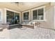 Relaxing covered patio with neutral toned furniture and a view of the dining room through the sliding glass doors at 3062 Echoed Rondel Ln, Henderson, NV 89044