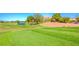 Expansive view of the golf course featuring a water hazard, lush green grass, and mountain views at 3335 American Mustang Ct, Las Vegas, NV 89122