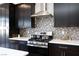 Close up of a modern kitchen featuring dark cabinets, stainless steel appliances, and a unique backsplash at 4066 Painted Lady Ave, Las Vegas, NV 89141