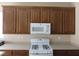 This kitchen has a white gas stove and microwave with wood cabinets above at 5240 Sweet William St, North Las Vegas, NV 89081