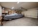 A spacious garage with cabinets, storage, and a car covered with a gray tarp at 5481 Lincolnwood Ct, Pahrump, NV 89061