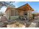 A tranquil backyard patio with a stone table, seating area, and covered wooden pergola at 5481 Lincolnwood Ct, Pahrump, NV 89061