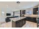 Open kitchen and living room, featuring an island, dark cabinetry and modern appliances at 6338 Selston Dr, North Las Vegas, NV 89081
