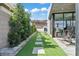 Contemporary backyard showcasing lush greenery and modern walkway with pavers leading to a workout room at 650 Scenic Cliff Dr, Henderson, NV 89012