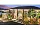 Striking exterior view features stone accents, lush landscaping, and expansive windows with a city skyline in the distance at 650 Scenic Cliff Dr, Henderson, NV 89012