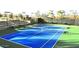 Bright blue community tennis court surrounded by lush greenery, complete with stadium seating at 650 Scenic Cliff Dr, Henderson, NV 89012