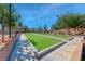 Well-maintained community bocce ball court with artificial turf and bordering sidewalk, surrounded by trees at 7012 Mercurio Ave, Las Vegas, NV 89131