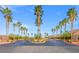 The community entrance features a roundabout, palm trees, and desert landscaping at 7354 Strutting Silver Ct, Las Vegas, NV 89131