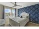 Bedroom with a white bed, and patterned wallpaper, brightened by natural light from a large window at 10004 Pasque Flower Ct, Las Vegas, NV 89178