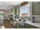 Stylish kitchen featuring green cabinets, stainless steel appliances, and a farmhouse sink under a bright window at 10004 Pasque Flower Ct, Las Vegas, NV 89178