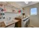 Well-lit laundry room with a sink, wooden countertop, floating shelves, and modern washer and dryer at 10004 Pasque Flower Ct, Las Vegas, NV 89178