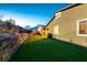 Green backyard features artificial turf, stone retaining wall, and outdoor lighting ideal for entertainment at 10125 Sequoia Falls Pl, Las Vegas, NV 89149