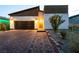 Front exterior of a modern home with a dark garage door, stone driveway, and desert landscaping at 10125 Sequoia Falls Pl, Las Vegas, NV 89149
