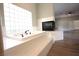Bright bathroom featuring a large tub, tiled surround, and a modern fireplace at 2111 Loro Ct, Las Vegas, NV 89117