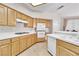 Well-lit kitchen featuring tile flooring, wood cabinets and modern white appliances at 2617 Huber Heights Dr, Las Vegas, NV 89128
