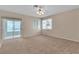 Bright living room with neutral walls, carpet flooring, ceiling fan, and sliding doors to the backyard at 2617 Huber Heights Dr, Las Vegas, NV 89128