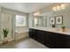 Bathroom with double vanity, framed mirrors, tiled floor, and soaking tub under a bright window at 2617 Romarin Ter, Henderson, NV 89044