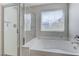Modern bathroom features a separate glass shower and soaking tub under a window at 2617 Romarin Ter, Henderson, NV 89044