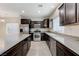 Modern kitchen featuring stainless steel appliances, dark cabinetry, and a tile backsplash at 2617 Romarin Ter, Henderson, NV 89044