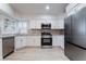Modern kitchen with stainless steel appliances, white cabinetry, granite countertops, and wood-look tile flooring at 289 Garwood Ct, Henderson, NV 89074