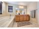 Well-lit bathroom featuring a large mirror, wooden cabinets, and a luxurious soaking tub at 6617 Fort William St, North Las Vegas, NV 89084