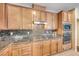 Well-lit kitchen features granite countertops, mosaic tile backsplash, stainless steel appliances, and wood cabinets at 6617 Fort William St, North Las Vegas, NV 89084