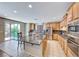 Open kitchen with stainless appliances, granite counters, wood cabinets, central island, and sliding door to the back patio at 6617 Fort William St, North Las Vegas, NV 89084