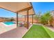 Covered patio with outdoor seating next to a yard with artificial turf and view of the pool at 6617 Fort William St, North Las Vegas, NV 89084