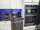 Kitchen area boasting stainless steel appliances, white cabinets, and black backsplash and countertops at 7091 Rhapsody Ln, Las Vegas, NV 89119